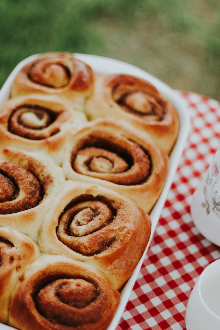 Delicious homemade cinnamon rolls on a checkered tablecloth outdoors. Perfect for breakfast or brunch.